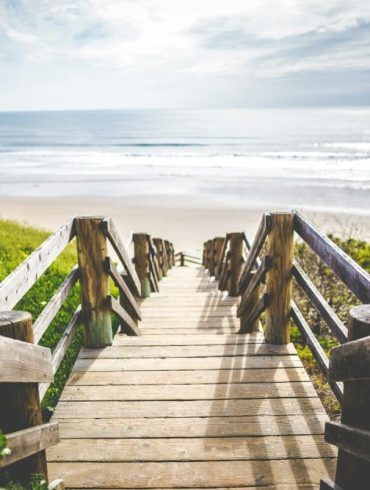 brown wooden walkway near beach during daytime